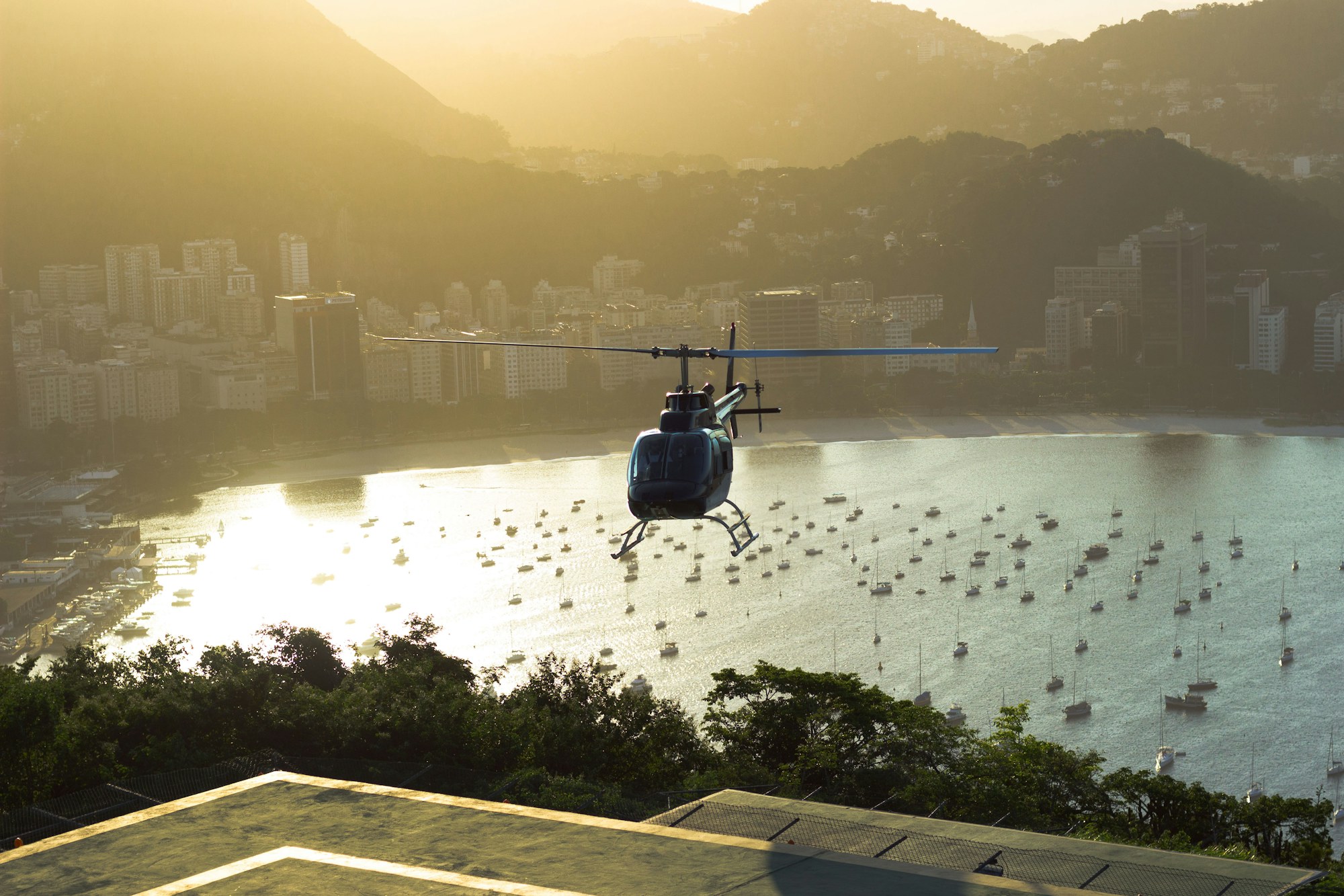 Helicopter over a bay and city skyline at golden hour